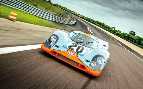 Ein ikonischer Porsche Rennwagen aus den 80ern, der Gulf-Porsche 917, rast auf einer Rennstrecke.