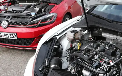 Dos Volkswagen Golf 7 GTI, uno rojo y otro blanco, con capós abiertos mostrando sus motores.