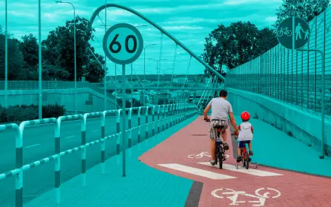 Ojciec i syn na rowerach jadą ścieżką rowerową. Obowiązują przepisy dla rowerzystów, w tym ograniczenie prędkości do 60 km/h.