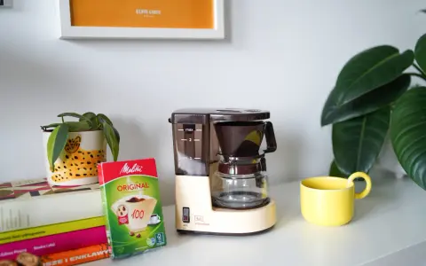 Kawiarka przelewowa Melitta Aromaboy gotowa do zaparzenia porannej kawy. Obok filtry i żółta filiżanka.
