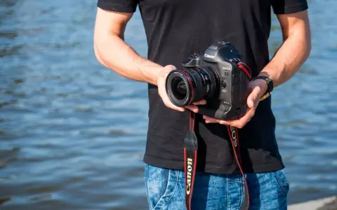 Mężczyzna trzyma aparat Canon EOS-1D Mark II z obiektywem, idealny do fotografii krajobrazowej dzięki matrycy **APS-C**.