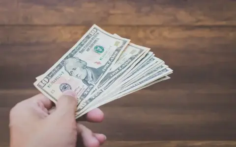 Dłoń trzyma plik banknotów dziesięciodolarowych. To może być zapłata za trzynastkę lub po prostu nagroda.