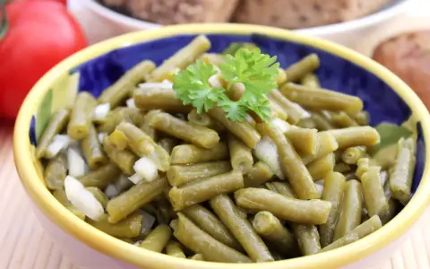 Bohnensalat rezept: Ein bunter Napf mit grünen Bohnen, Zwiebeln und Petersilie, bereit zum Servieren.