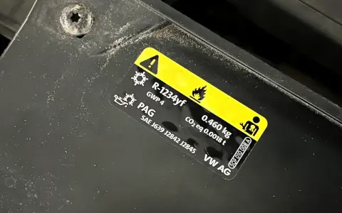 Naklejka informuje o ilości czynnika klimatyzacji R-1234yf (0.460 kg) i typie oleju PAG w samochodzie VW AG.