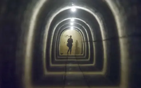 Sylwetka w tunelu Międzyrzeckiego Rejonu Umocnionego. Kolejne łuki i światła tworzą perspektywę.