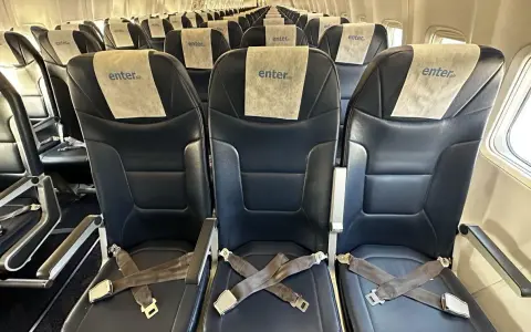 Puste, ciemne fotele w samolocie Enter Air z pasami bezpieczeństwa.