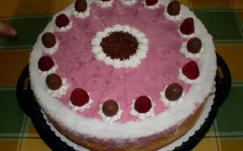 Eine köstliche Kokos Himbeer Torte, verziert mit Schokolade und frischen Himbeeren, bereit zum Genießen.