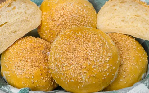Koszyk pełen pysznych, złotych bułek bez drożdży, posypanych sezamem. Idealne na burgery lub jako dodatek do posiłku.