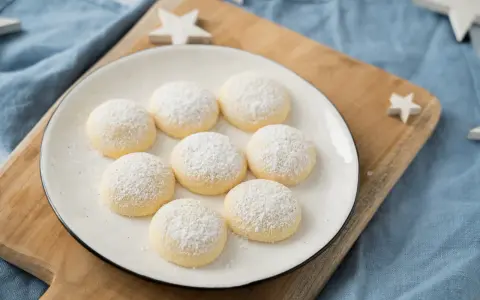 Zarte, mit Puderzucker bestäubte Kekse auf einem Teller, bereit zum Genießen. Perfekt zum Kekse backen für gemütliche Stunden.