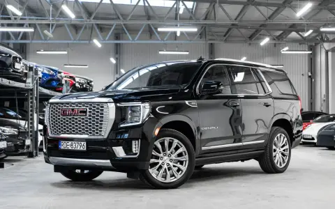 Czarny GMC Yukon Denali lśni w salonie samochodowym, gotowy na przygodę.