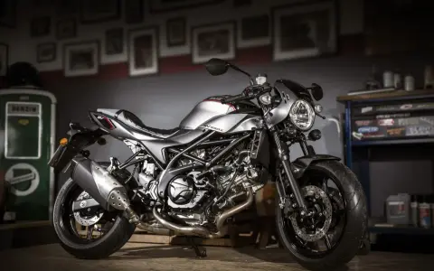 Srebrny motocykl Suzuki SV650X z czarną ramą i detalami, stojący w garażu.