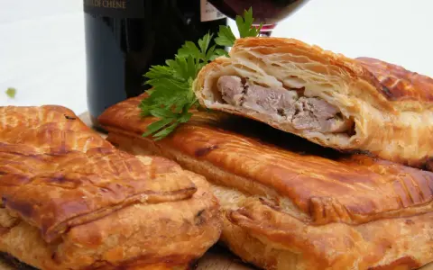 Pâté en croûte, une spécialité lorraine savoureuse, garni de viande et d'herbes, prêt à être dégusté avec un verre de vin.