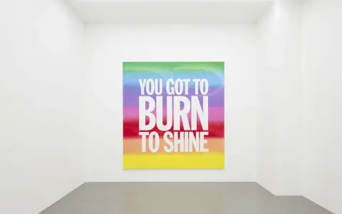 Œuvre de John Giorno dans une galerie, avec le message "YOU GOT TO BURN TO SHINE" sur un fond arc-en-ciel.