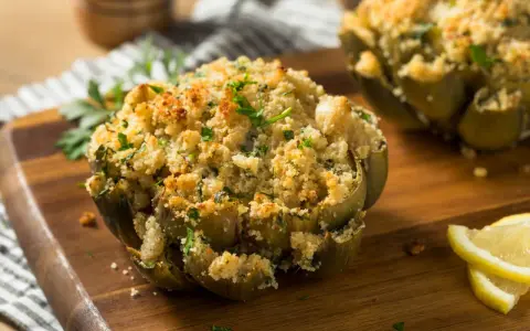 Carciofi ripieni e dorati, cotti alla perfezione nella friggitrice ad aria, guarniti con prezzemolo fresco e spicchi di limone.