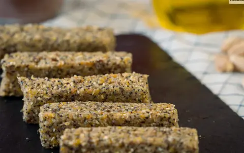 Barritas energéticas caseras de cereales y semillas en una tabla de pizarra.