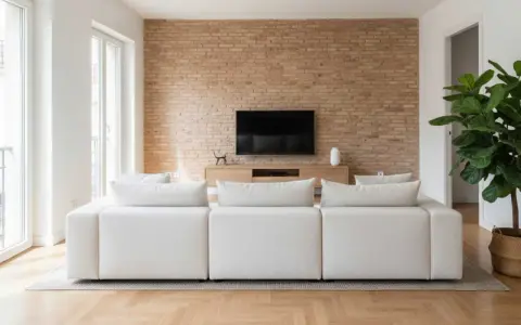 Sofá blanco modular frente a pared de ladrillo y mueble de TV. La **dirección de obra** supervisó este moderno y acogedor salón.