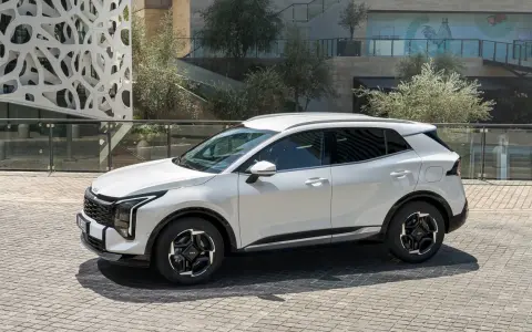 Biała Kia Sportage hybryda na tle nowoczesnej architektury. Stylowy SUV gotowy na miejskie wyzwania.