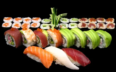 Różnorodne sushi: nigiri z łososiem, tuńczykiem i białą rybą, rolki z awokado, krewetką, tuńczykiem i ogórkiem. Idealne na początek nauki, jak jeść sushi.