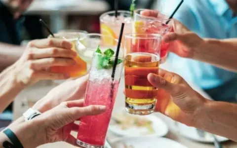Ludzie wznoszą toasty kolorowymi drinkami. Zastanawiasz się, ile alkoholu można wziąć do Norwegii?