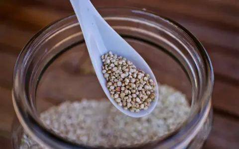 Eine Löffelspitze voller Quinoa, dem gesunden Korn, das in einem Glas aufbewahrt wird.