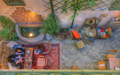 Cortile interno con fontana, piante e arredi colorati. Un luogo ideale a Palermo dove si mangia e si balla, tra tappeti e luci soffuse.