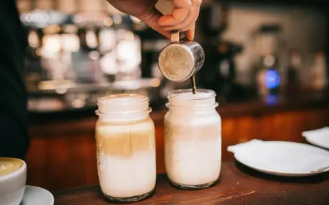 Barista bereitet Latte Macchiato zu. Die Frage "wie viel Kalorien hat ein Latte Macchiato" beschäftigt viele Genießer.