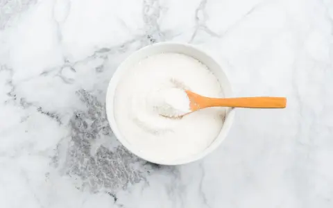 Schüssel mit weißem Pulver, das Kollagenpeptide enthält. Die Wirkung von Kollagenpeptiden ist vielfältig.