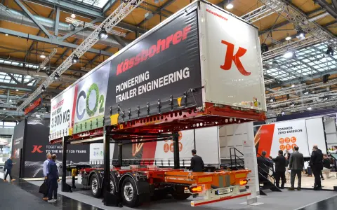 Nowa naczepa Kässbohrer z napisem "Pioneering Trailer Engineering". W tle ludzie zwiedzają targi.