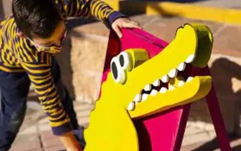 Un niño interactúa con un cocodrilo amarillo de utilería, parte de un espectáculo de teatro infantil en Málaga.