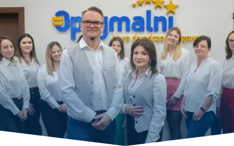 Zespół uśmiechniętych doradców podatkowych w białych koszulach przed logo firmy.