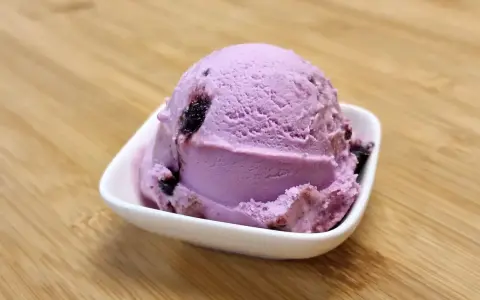 Une boule de glace violette aux fruits, parfaite pour une recette glace amarena maison.