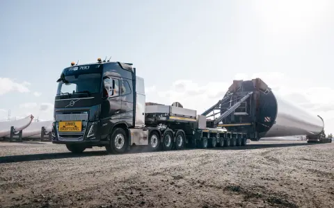 Potężny Volvo FH16 transportuje ogromną łopatę turbiny wiatrowej.