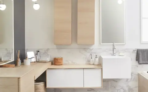 Salle de bain moderne avec un lavabo évier suspendu, des meubles en bois clair et un grand miroir éclairé.