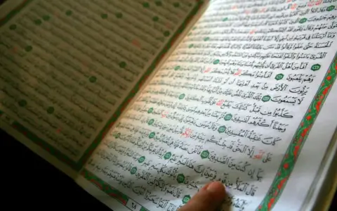 Ein Finger zeigt auf eine Seite des Korans. Die Frage, wer hat den Koran geschrieben, wird durch die heiligen Schriften beantwortet.