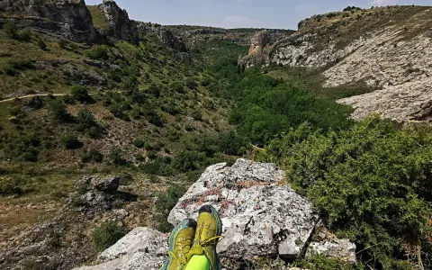 Botas de trail running sobre roca, contemplando el cañón del río Dulce en Guadalajara.