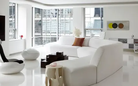 Soggiorno minimalista con divano bianco curvo, sedie futuristiche e tavolini geometrici, un vero esempio di space age design.