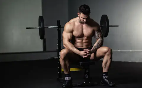 Muskulöser Mann sitzt nach dem Training auf einer Bank, bereit für die Definitionsphase seines Trainingsplans.