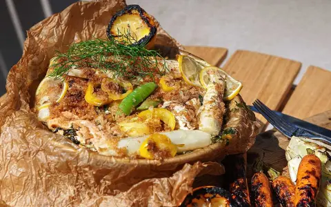 En saftig fiskpaket på grillen med citron, sparris och dill. Serveras med grillade grönsaker.