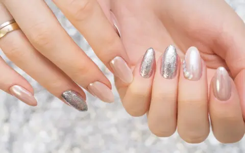 Mani curate con unghie eleganti, un mix di nude perlato e glitter argento, perfetti colori smalto primavera.