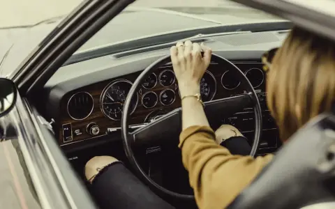 Mujer al volante de un coche clásico. De repente, la dirección asistida dura, dificultando el giro.