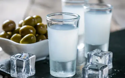Raki, ein Getränk, das oft mit Griechenland assoziiert wird, wird aus Trauben hergestellt. Hier sind Gläser mit Raki, Eiswürfel und Oliven.