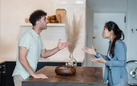 Pareja discutiendo en la cocina, un momento de reflexiones de pareja en crisis. Sus gestos y expresiones muestran tensión.