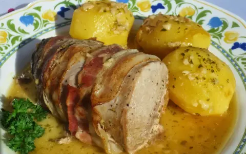 Solomillo al ajillo envuelto en bacon, servido con patatas doradas y perejil fresco. ¡Un plato delicioso!