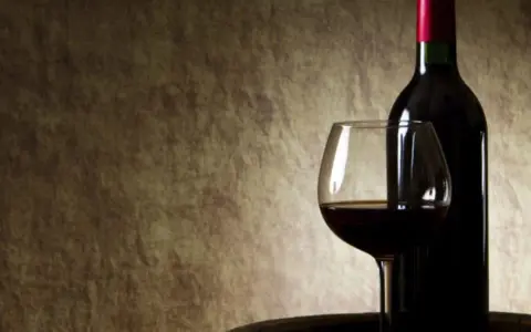 Kieliszek z czerwonym winem i butelka na tle. Czy czerwone wino się chłodzi?