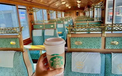 Enjoying a Starbucks coffee in the opulent, Belle Époque-style interior of a train, a stark contrast to modern panoramic views.