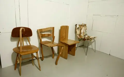 Tre unika stolar står uppradade. En av dem, med en böjd rygg, påminner om en design av Finn Ahlgren.