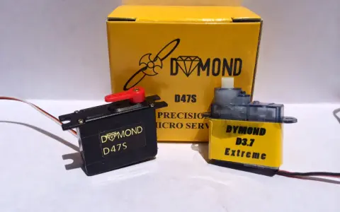 Zwei Servos, ein schwarzer Dymond D47S und ein gelber Dymond D3.7 Extreme, stehen vor einer gelben Box mit der Aufschrift "Dymond D47S".