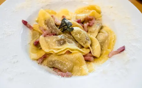 Ravioli ripieni, un piatto tipico bergamasco, conditi con pancetta croccante e salvia.