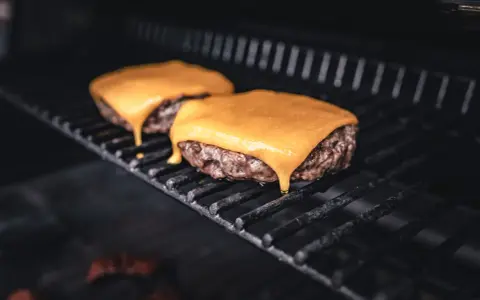 Zwei saftige Burger-Patties auf dem Grill, mit leckerem cheddar schmelzen, der langsam heruntertropft.