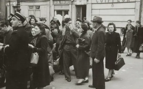 Une foule se presse devant "Union Vinicole" et "Coiffeur". L'atmosphère est tendue, évoquant la rafle du billet vert.